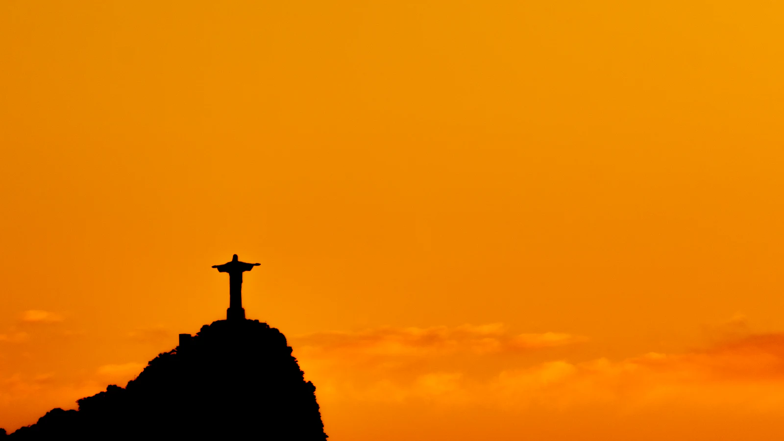 Christ the Redeemer silhouetted above Rio de Janeiro at golden hour